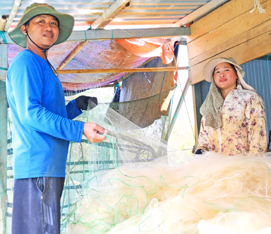 Trần Văn Tuấn and his wife shaking out anchovy nets after fishing. Photo: Đồng Lai
