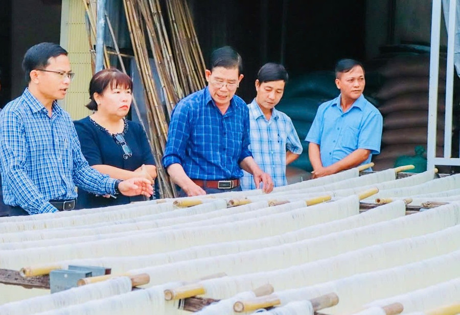 Secretary of the Ia Hiao Commune Party Committee Phạm Văn Phương (far left) visits a local dried noodle production facility. Photo: ĐVCC 2-1.jpg