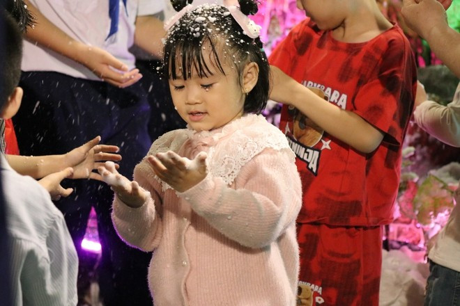 A child delighted by 'falling snow' at Tan Duc Parish (Phuoc Long Ward, Ho Chi Minh City).
