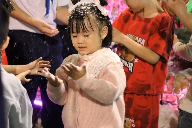 A child delighted by 'falling snow' at Tan Duc Parish (Phuoc Long Ward, Ho Chi Minh City).