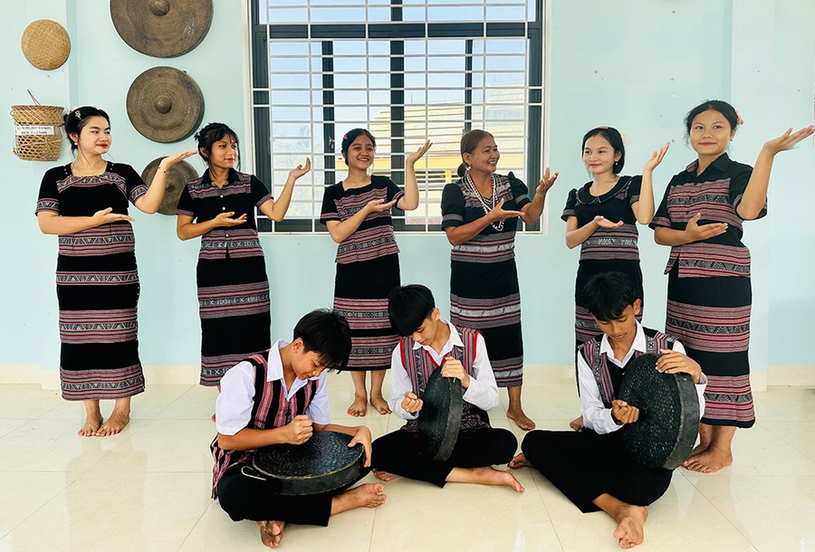 Young people practice a gong performance, with Mrs. Tuyết (back row, third from right) guiding them in singing and dancing. Photo: D.Đ Thực hành một bài đánh chiêng, hướng dẫn cùng hát và múa.