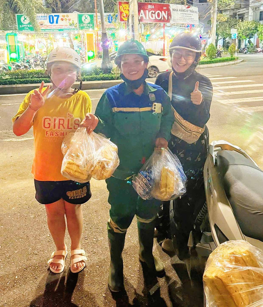 Nhóm chị em của Trần Phương Trinh trao bánh mì, sữa cho các lực lượng đang làm nhiệm vụ. Ảnh: Hải Yến