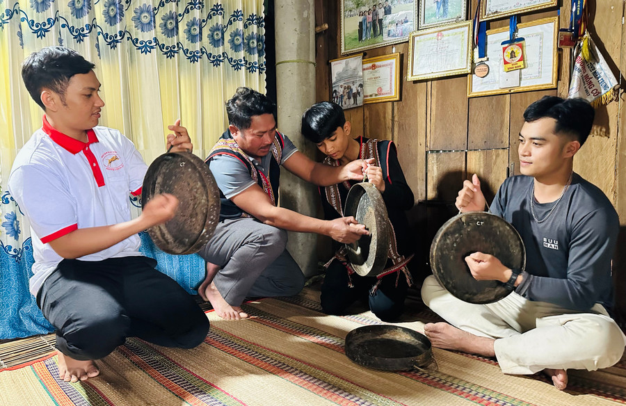 Nghệ nhân Thanh Văn Huấn (thứ hai từ trái sang) cầm tay hướng dẫn cho thanh thiếu niên trong làng cách đánh các bài chiêng. Ảnh: P.C.H