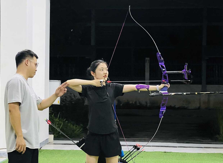 Coach Tiêu Viết Trường An (far left) instructs student Nguyễn Thị Kiều Trang in archery techniques. Photo: M.N Coach Tiêu Viết Trường An (far left) instructs student Nguyễn Thị Kiều Trang in archery techniques. Photo: M.N