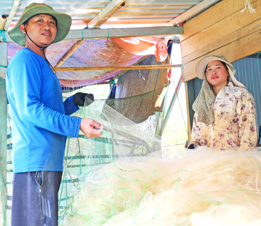 Trần Văn Tuấn and his wife shaking out anchovy nets after fishing. Photo: Đồng Lai