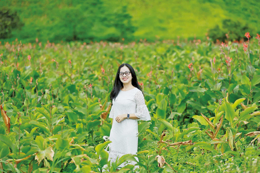 Ms. Bùi Ngọc Ngà posing with canna lilies at the foot of Chư Đang Ya Mountain.